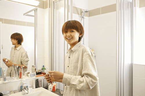 Boy putting tooth paste on his tooth brush